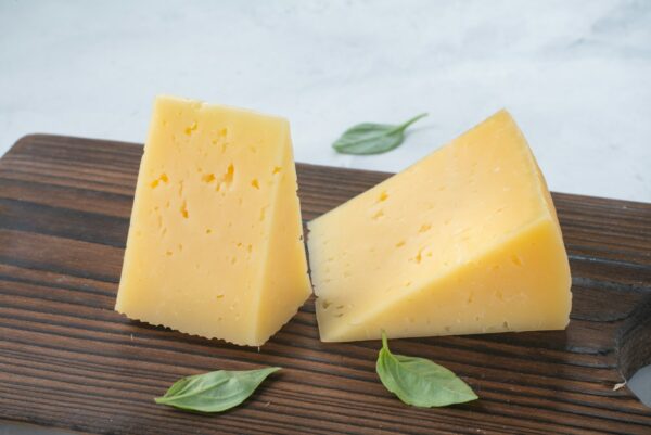 a couple of pieces of cheese sitting on top of a wooden cutting board